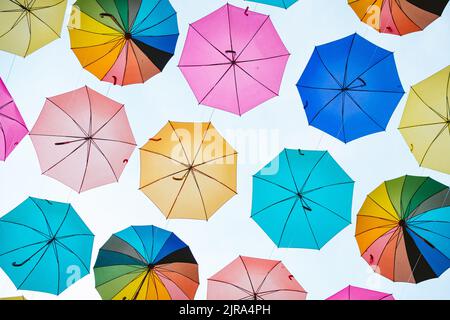 Bunte Regenschirme Hintergrund. Bunte Regenschirme, die am Himmel hängen, dienen als Straßendekoration. Stockfoto