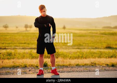 SPORTIV Mann Läufer Ruhe nach dem Training im Freien, suchen Uhr mit einem schönen Hintergrund Stockfoto