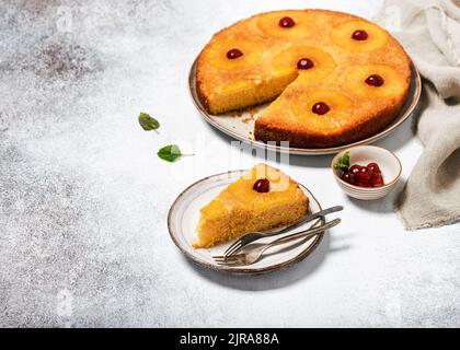 Stück umgedrehter Ananaskuchen mit kandierten Kirschen und Karamell. Tropisches Dessert im Sommer. Selektiver Fokus. Speicherplatz kopieren. Stockfoto