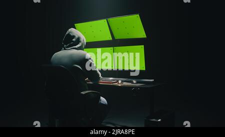 Konzept Aufnahme von anonymen Mann im Hoodie schreiben Code, um Datenbank zu hacken, während am Schreibtisch mit Computermonitoren sitzen, mit grünen Bildschirmen chromakey in dunklen Raum der Hacker-Basis Stockfoto
