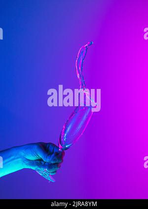 Gruß Toast. Authentisches, handgegossene, reine Flüssigkeit aus Wein- oder Sektglas über einen hellblau-rosa Hintergrund in Neonlicht. Stockfoto