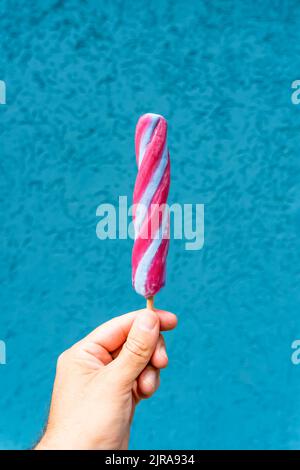 Eiscreme-Kegel in der Hand auf minimalem Farbhintergrund isoliert. Sommer, Essen, Süßigkeiten, Eis-Konzept. Hochwertige Fotos Stockfoto