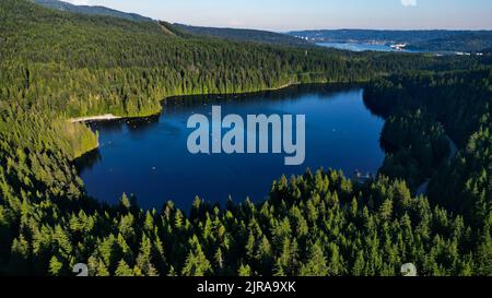 Eine wunderschöne Aussicht auf den Sasamat Lake, umgeben von dichten Bäumen in Port Moody, Kanada Stockfoto