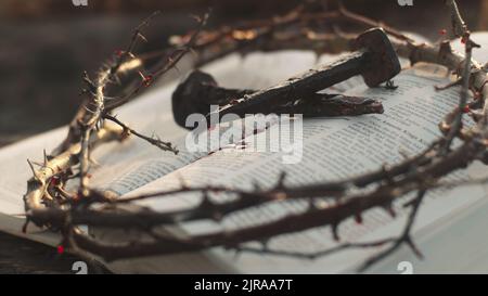 Closeup blutige Nägel und Dornenkrone auf der geöffneten Heiligen Bibel nach Jesus Christus Kreuzigung gelegt Stockfoto