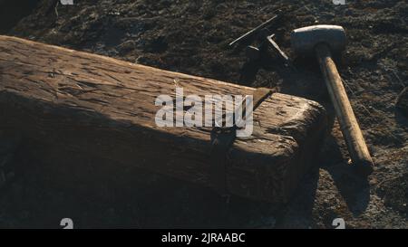 Hoher Winkel von Holzkreuz für Jesus Christus Hinrichtung auf dem Boden in der Nähe von Hammer und Nägel an windigen Tag gelegt Stockfoto