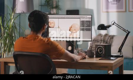 Rückansicht eines anonymen Mannes, der 3D ein Videogame-Modell erstellt, während er am Tisch sitzt und zu Hause an einem Remote-Projekt arbeitet Stockfoto