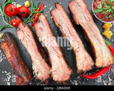 Gegrillte Schweineribs auf schwarzem Schieferbrett. Draufsicht, Nahaufnahme Stockfoto