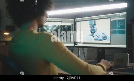 Mann mit lockigen Haaren, der 3D Modell eines futuristischen Roboters für Videospiele erstellt, während er spät in der Nacht zu Hause an einem Remote-Projekt arbeitet Stockfoto
