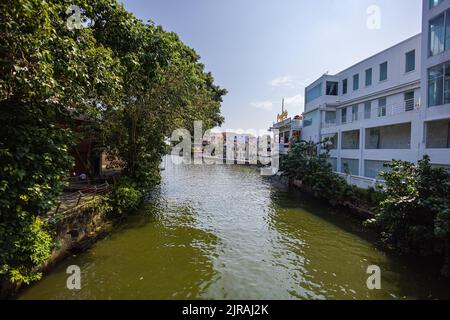 Malacca, Malaysia - 10. August 2022: Entlang des Flusses Melaka in der Altstadt. Bars und Restaurants säumen den Flusslauf. Bäume säumen den Fluss b Stockfoto