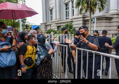 Putrajaya, Malaysia. 23. August 2022. Ein Polizeibeamter fordert die Menge auf, Platz für die ankommende Autokolonne zu machen, von der angenommen wurde, dass sie zuerst Malaysias ehemaligen Premierminister Najib Razak in das Kajang Gefängnis eskortiert, um seine Strafe zu beginnen. Das oberste Gericht von Malaysiaís bestätigte die Verurteilung des ehemaligen Premierministers Najib Razak und die 12-jährige Haftstrafe wegen Korruption im Finanzskandal von 1MDB. Kredit: SOPA Images Limited/Alamy Live Nachrichten Stockfoto