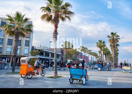 BARCELONA, SPANIEN -18. MAI 2018: Rikscha mit Touristen auf der Allee in der Nähe des Meeres Stockfoto