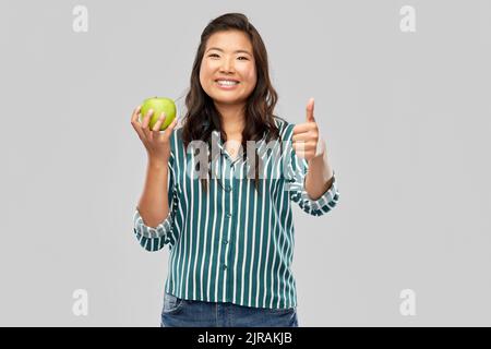 Glücklich lächelnde asiatische Frau hält grünen Apfel Stockfoto