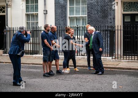 London, Großbritannien. 23 August 2022 . Premierminister Boris Johnson begrüßt die Floristen, die die Tür der Downing Street 10 mit Sonnenblumen, dem nationalen Symbol der Ukraine, zum Unabhängigkeitstag der Ukraine am 24. August schmückten. Kredit. amer Ghazzal/Alamy Live Nachrichten Stockfoto