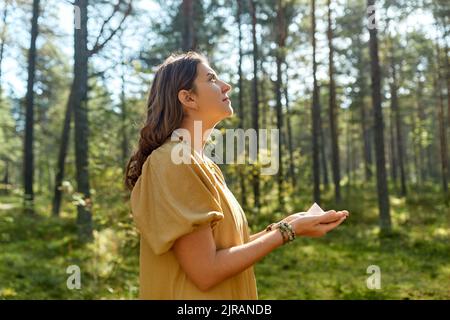 Junge Frau oder Hexe, die Pyramide im Wald hält Stockfoto