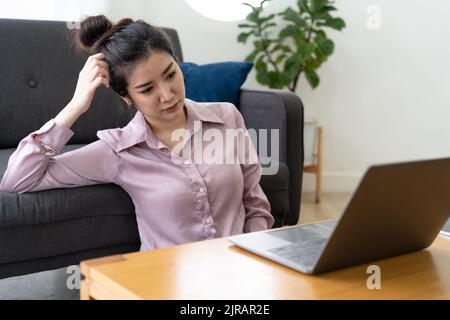 Gestresste asiatische Frau Kopfschmerzen bei der Arbeit mit Laptop-Computer zu Hause. Gestresst und depressiv Stockfoto