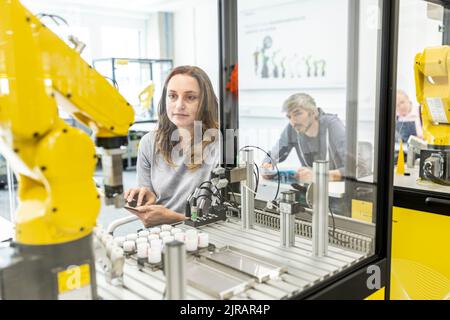 Frau, die in einer Roboterfabrik mit einem digitalen Tablet arbeitet Stockfoto