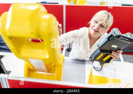 Ingenieurin, die mit digitaler Steuerung am Industrieroboter arbeitet Stockfoto
