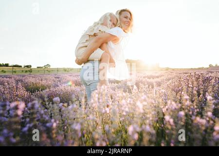 Glückliche Mutter gibt Huckepack Fahrt zu Tochter Stockfoto