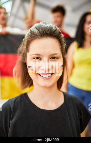 Lächelnde Frau mit der deutschen Flagge auf dem Gesicht bei einem Sportereignis im Stadion Stockfoto