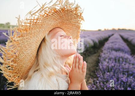 Lächelndes Mädchen mit geschlossenen Augen und Gebet im Lavendelfeld Stockfoto
