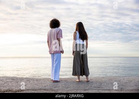 Junges Paar, das vom Pier aus auf das Meer blickt Stockfoto