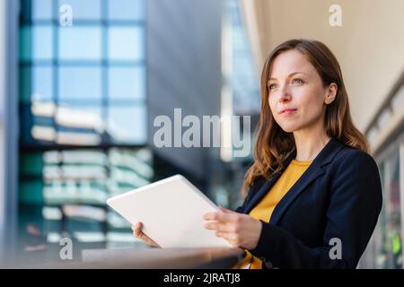 Kontemplative Geschäftsfrau mit Tablet-PC Stockfoto