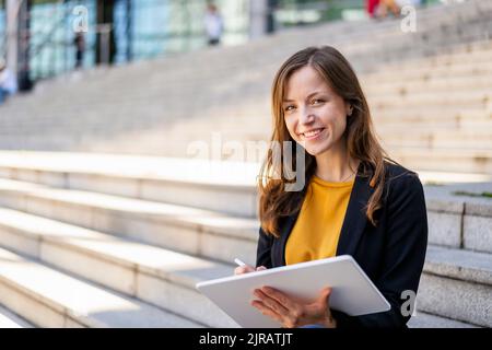 Lächelnde Geschäftsfrau mit Tablet-PC auf der Treppe Stockfoto