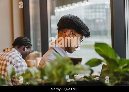 Junge Freiberuflerin in Brillen, die im Café arbeitet Stockfoto