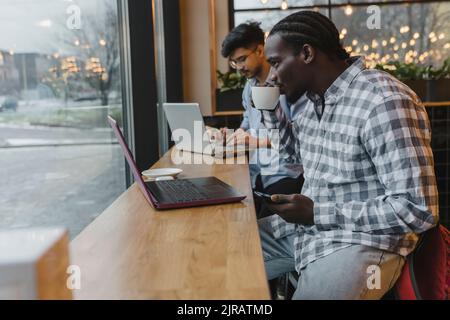 Junger Freiberufler, der Kaffee am Tisch im Café trinkt Stockfoto