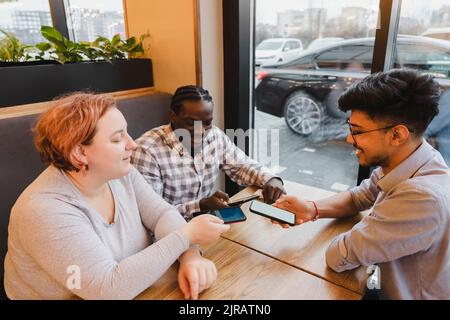 Glückliche Freunde teilen Daten über Smartphones im Café Stockfoto