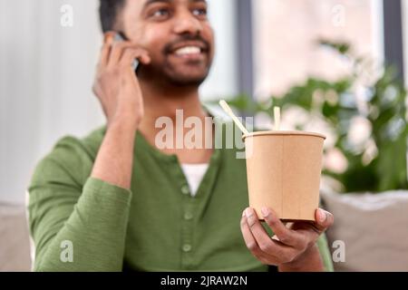 Mann mit Essen zum Mitnehmen ruft zu Hause am Telefon an Stockfoto