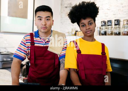 Mann und Frau tragen Schürzen im Café Stockfoto