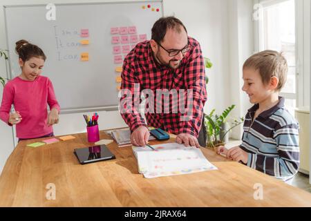 Lächelnder Lehrer, der Jungen zu Hause Englisch beibringt Stockfoto