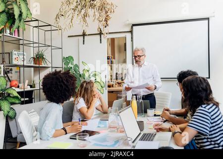 Manager hält Dokumente, die mit Kollegen im Büro besprechen Stockfoto