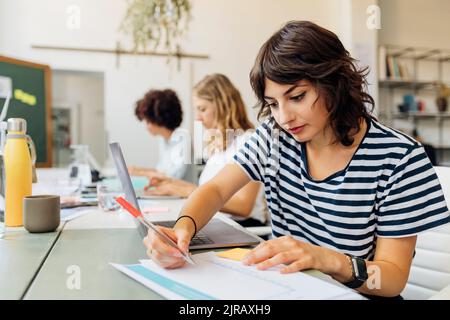 Geschäftsfrau mit Laptop, die im Büro Berichte vorbereitet Stockfoto