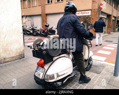 Ein Mann auf einer weißen italienischen Vespa in Barcelona Stockfoto