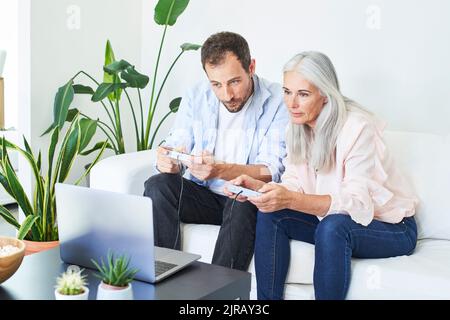 Reife Frau mit Sohn spielt Videospiel zu Hause Stockfoto