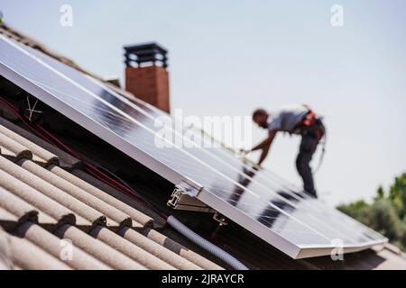 Elektriker, der Solarmodule auf dem Dach installiert Stockfoto