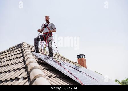 Handwerker, der Solarzellen auf dem Dach installiert Stockfoto