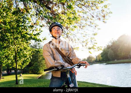 Kontemplative Frau, die mit dem Fahrrad im Park steht Stockfoto