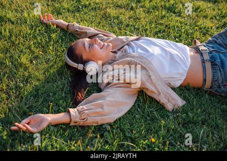 Frau, die sich im Park auf Gras legt Stockfoto