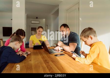 Familie, die drahtlose Technologien auf dem Tisch zu Hause verwendet Stockfoto