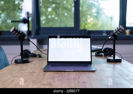 Laptop inmitten von Headsets auf dem Schreibtisch im Radiosender Stockfoto