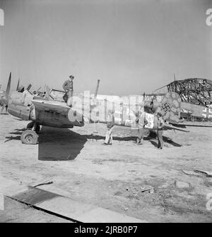 Ein Vintage-Foto um den Mai 1943, das amerikanische Piloten zeigt, die ein zerstörtes deutsches Henschel HS 129-Panzerabwehrflugzeug in El Aouiana, Tunesien, nach der Niederlage der Axis-Streitkräfte in Nordafrika im Zweiten Weltkrieg inspizieren Stockfoto