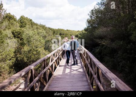 Reifes Paar, das auf einer Fußgängerbrücke inmitten von Bäumen steht Stockfoto