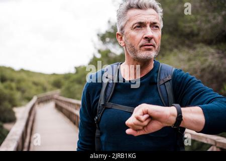 Reifer Mann mit Armbanduhr, der auf dem Steg steht Stockfoto