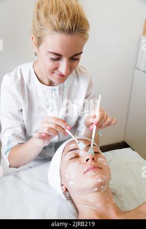 Close-up Kosmetikerin Arzt Hand machen Anti-Age-Verfahren gelten Peeling Säure, junge attraktive weibliche Klientin in der Beauty-Klinik. Gesundheitstherapie Stockfoto