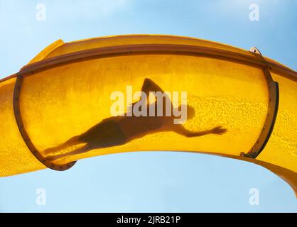 Silhouette einer Person, die die Wasserrutsche hinunterrutscht Stockfoto