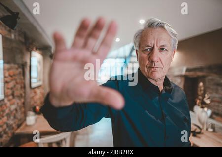 Älterer Mann macht im Café eine Stoppgeste Stockfoto