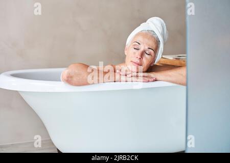 Frau mit Augen geschlossen zum Entspannen in der Badewanne Stockfoto
